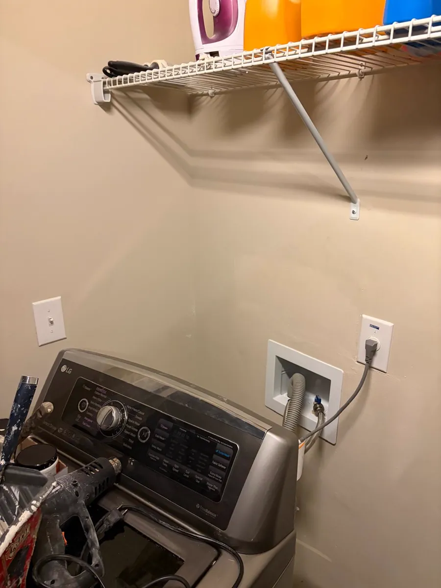 Finished laundry room wall with washer hoses connected to the recessed outlet box